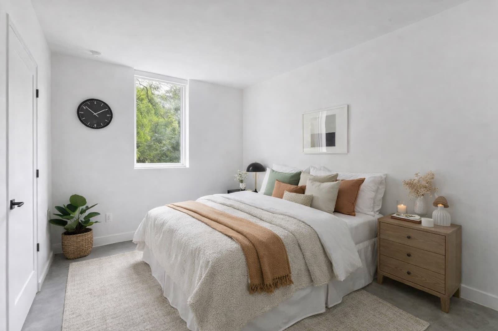 Minimalist bedroom with oak nightstand and earth-tone throws at Capitol Living